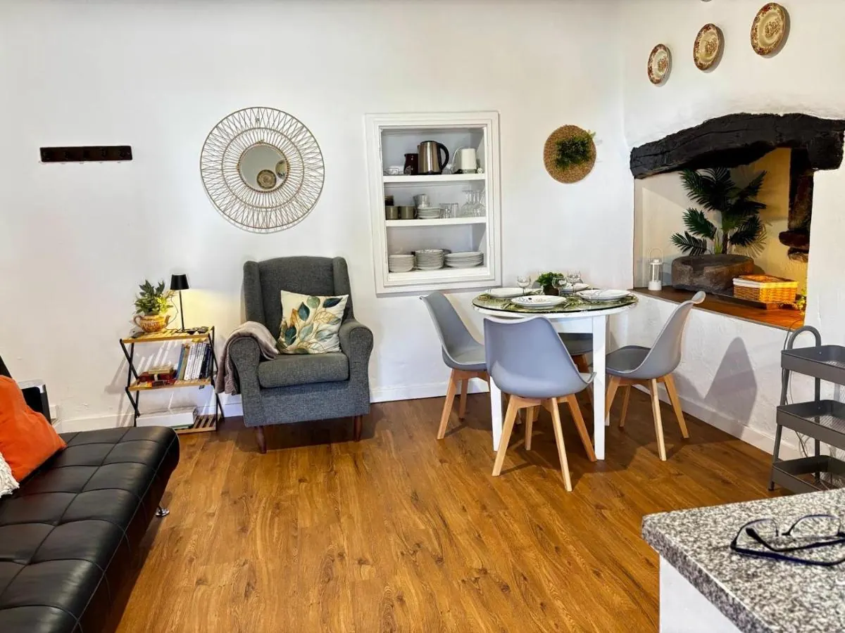 Sala com sofá, poltrona, mesa e a lareira antiga ao fundo