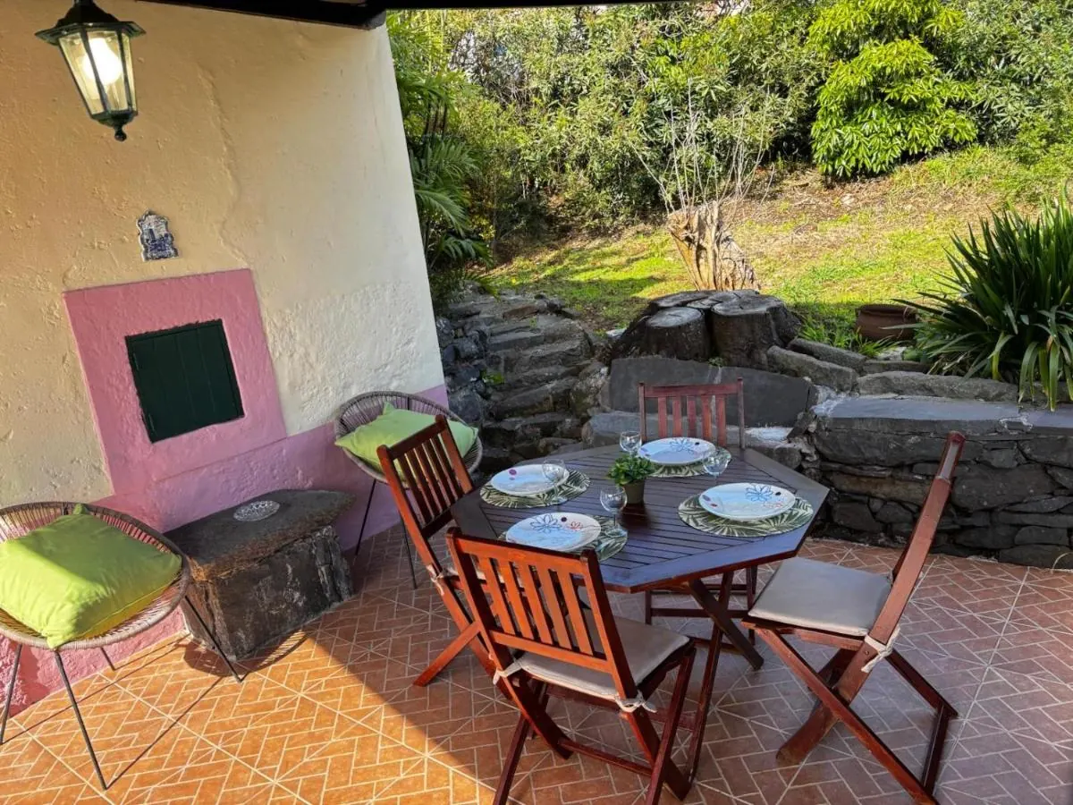 Terraço com mesa posta, ao lado do forno antigo de parede amarela e cantaria cor-de-rosa